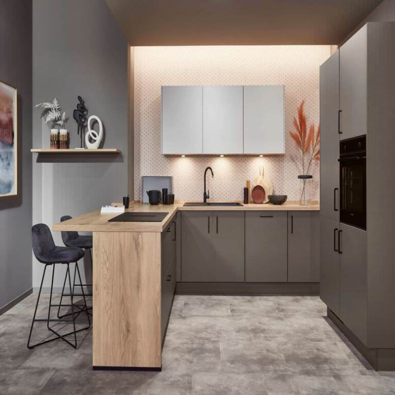 Exklusive U-Küche mit Holztresen – Küchenstudio Magdeburg Exklusive U-Küche in Grau mit Tresen aus Holz, Barhockern und indirekter Beleuchtung