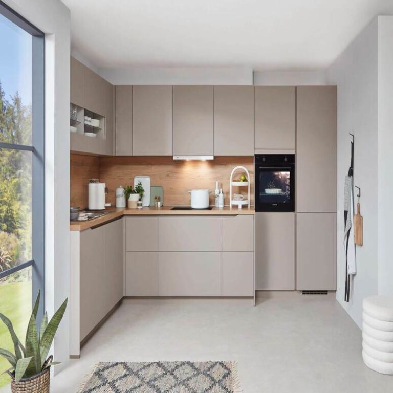 Musterküche in Kaschmir Musterküche in Kaschmir als L-Küche mit Holzrückwand und Backofen im Hochschrank – Küchenstudio Magdeburg